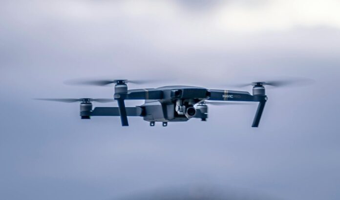 Ilustrācija ar debesīs lidojošu dronu