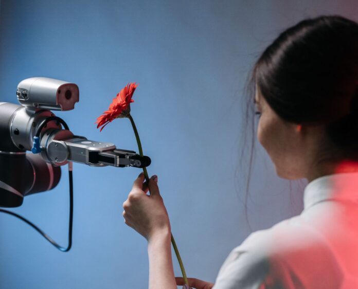 Ilustratīvs attēls – sieviete dod ziedu robotam